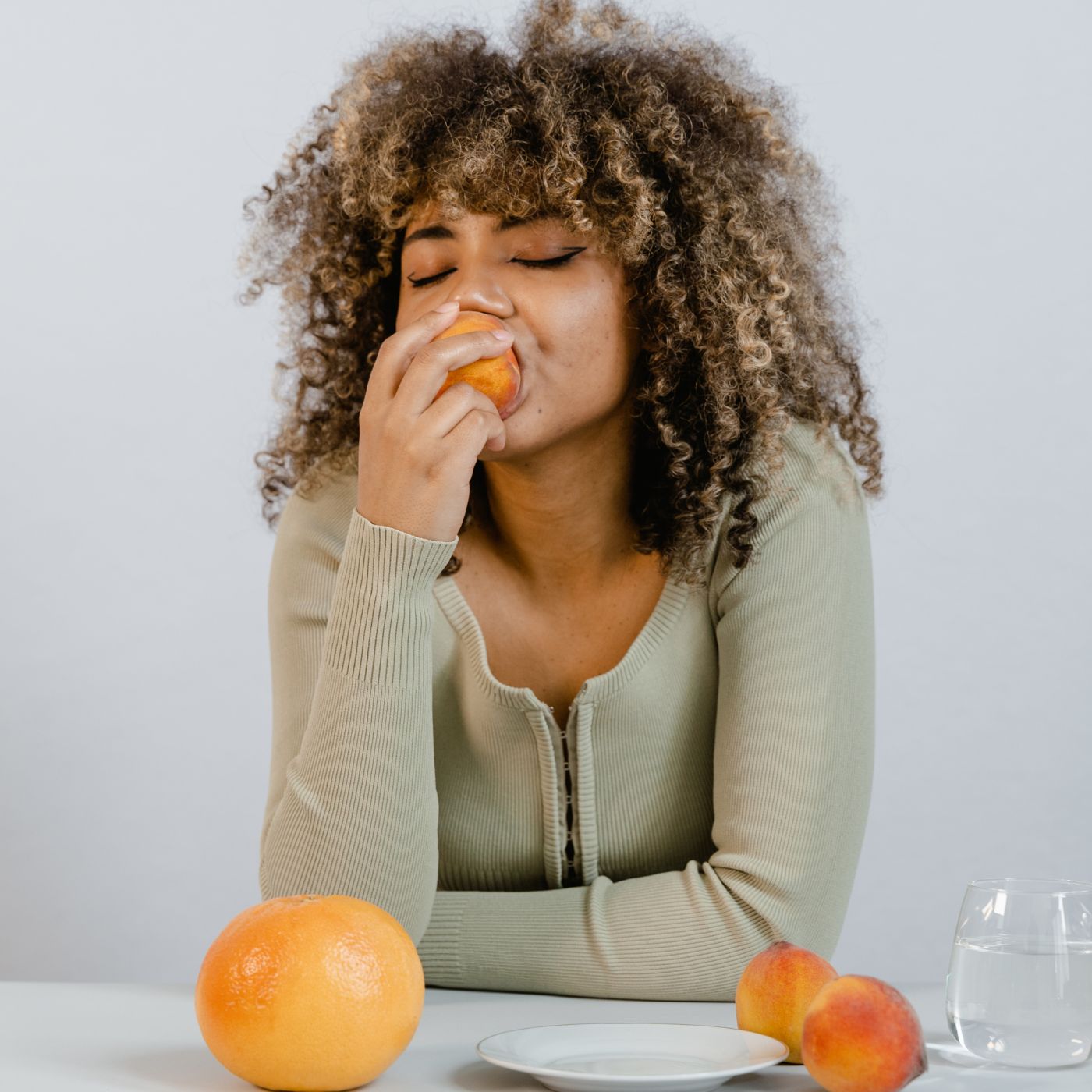 weiblich gelesene Person beißt in einen Pfirsich, gesunde ernährung für die haare, ernährung bei haarausfall