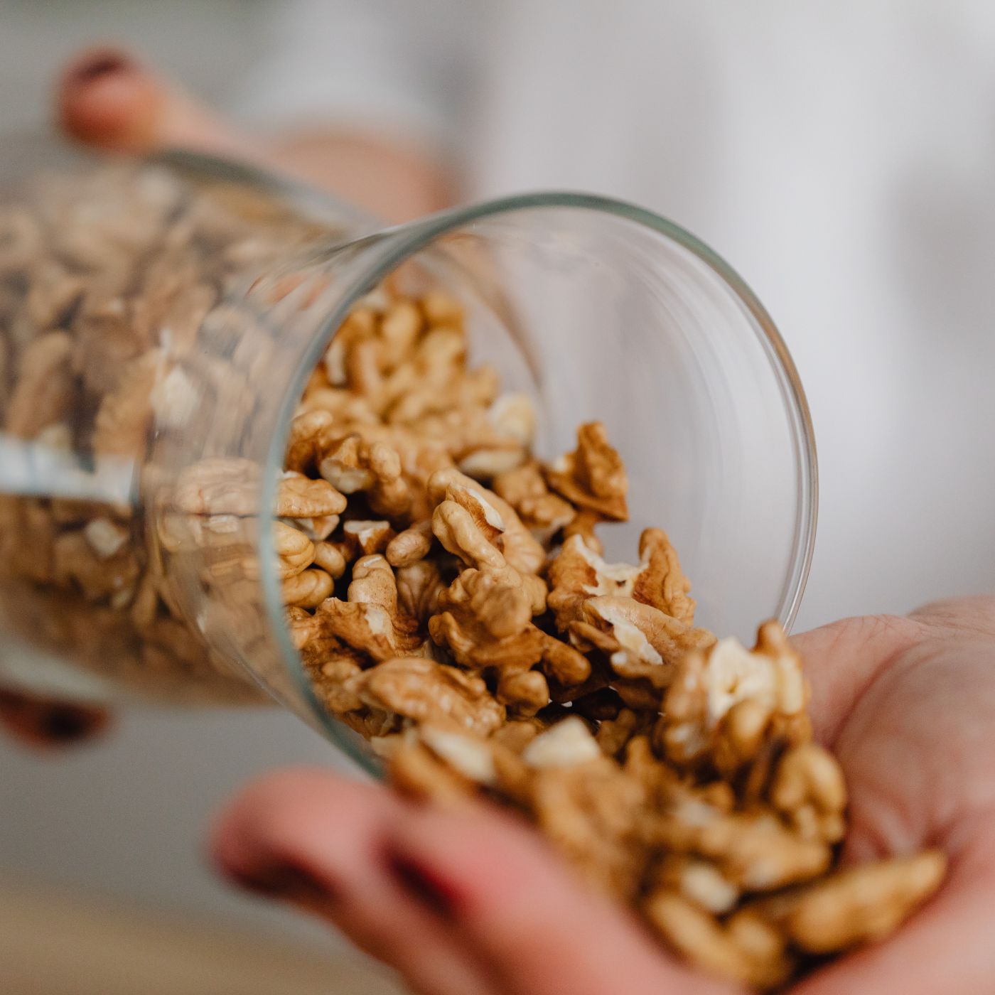 Glas mit Walnüssen, die in eine Hand geschüttet werden