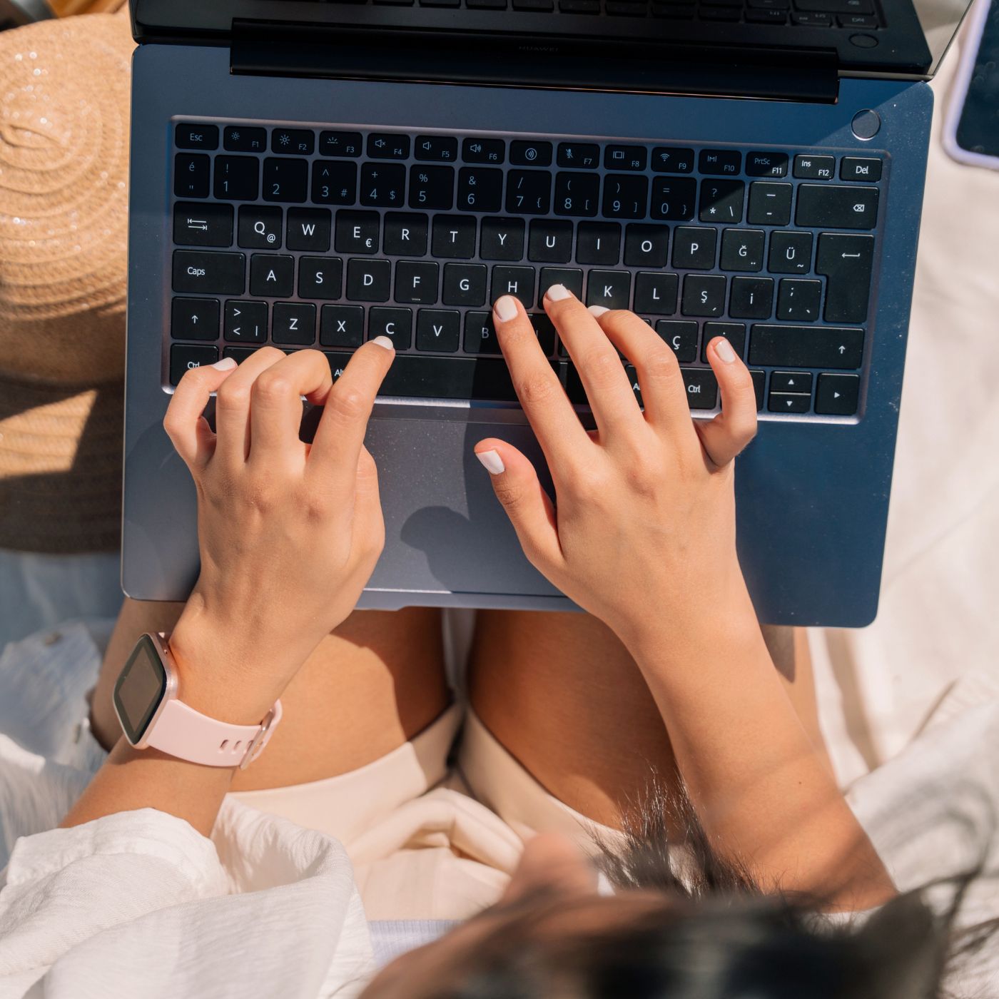 weiblich gelesene Person tippt auf Laptop, der auf ihren Beinen liegt