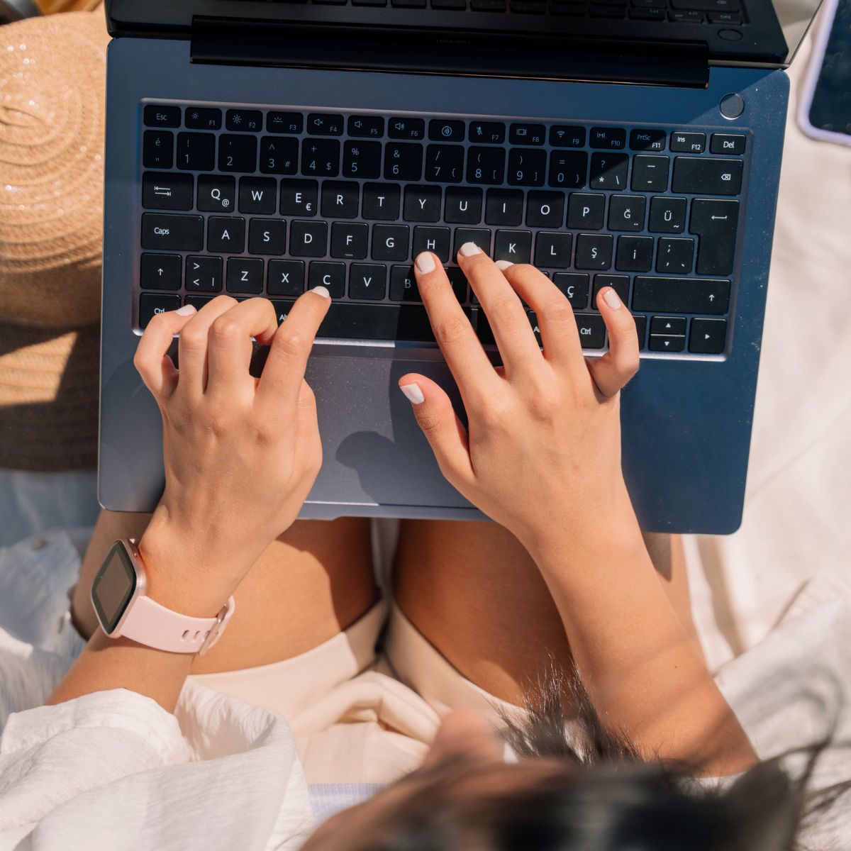 weiblich gelesene Person tippt auf Laptop, der auf ihren Beinen liegt